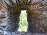 Štěrbinový otvor v plášťové hradbě směřující k přítupové cestě.